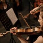 brunette woman playing on violin in orchestra