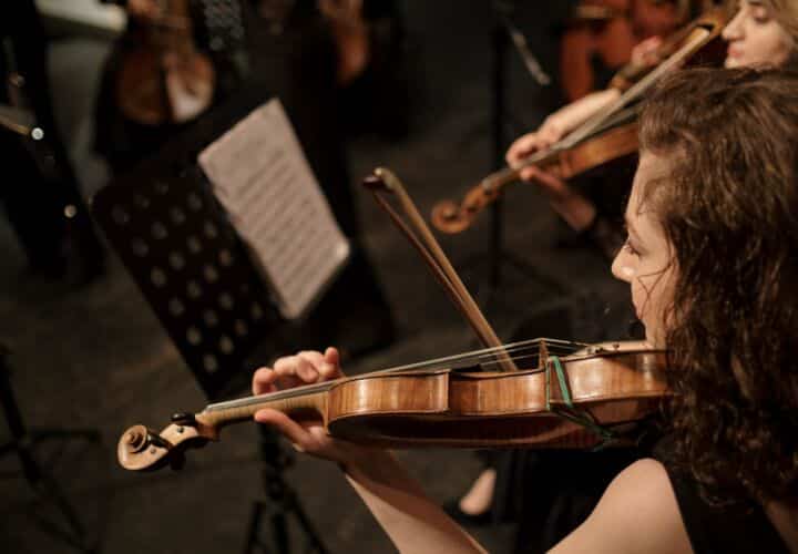 brunette woman playing on violin in orchestra