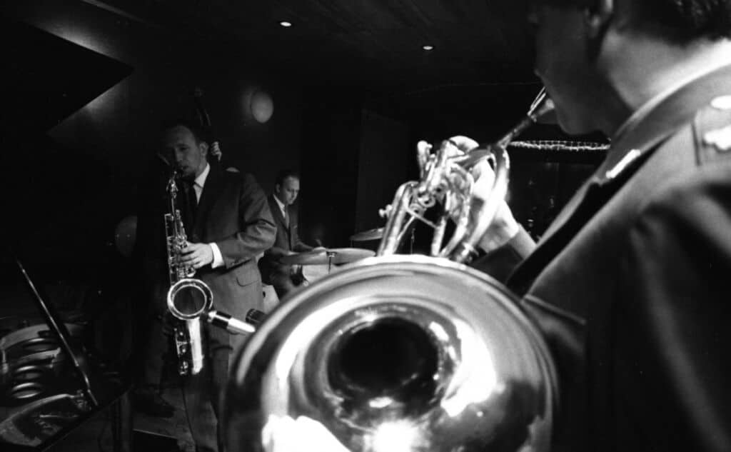 Jazz ensemble with trombone, tenor saxophone, piano and drums performing in a club