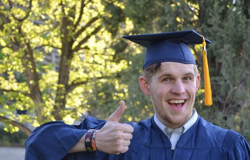Graduating student holding a thumbs up